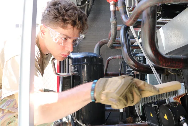 Airman 1st Class Colin Haniffy, an HVAC Technician, assigned to the 108th Civil Engineering Squadron, brushes rust off the interior of an air conditioning unit at Lajes Field, Portugal, on July 2, 2025. 108th CE members practiced their skills, and assisted with base-wide repairs during a deployment. People in an HVAC contractor business: recruit, train, keep